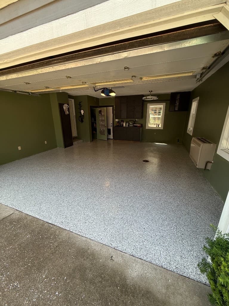 After coating: grey flake garage floor with high-gloss finish and dark green walls.