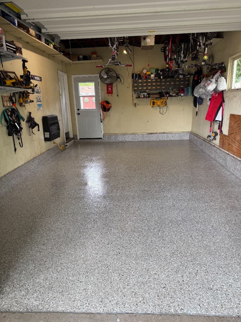After coating: grey white and black flake floor with high-gloss cove base finish.