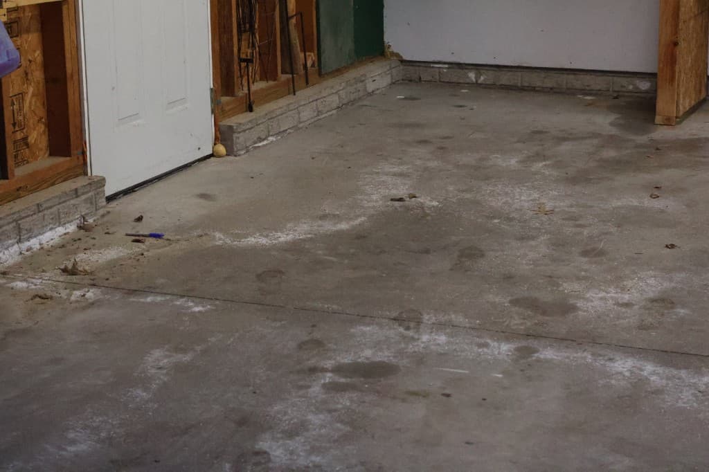 Before coating: stained garage concrete near wall.