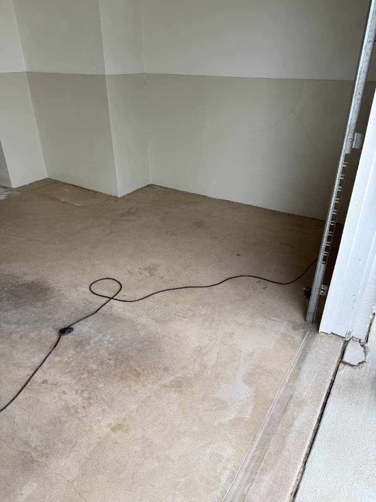 Before coating: stained tan garage floor with plain two-tone walls.